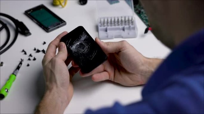 技术人员手中的屏幕破裂的智能手机。电子维修服务