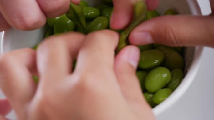 在白碗里吃绿色大豆。