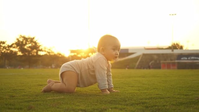 可爱的宝宝在外面草地上爬行。可爱的蹒跚学步的孩子在户外爬行
