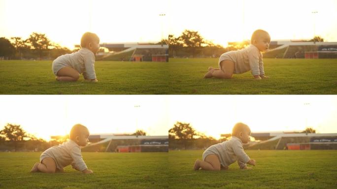 可爱的宝宝在外面草地上爬行。可爱的蹒跚学步的孩子在户外爬行