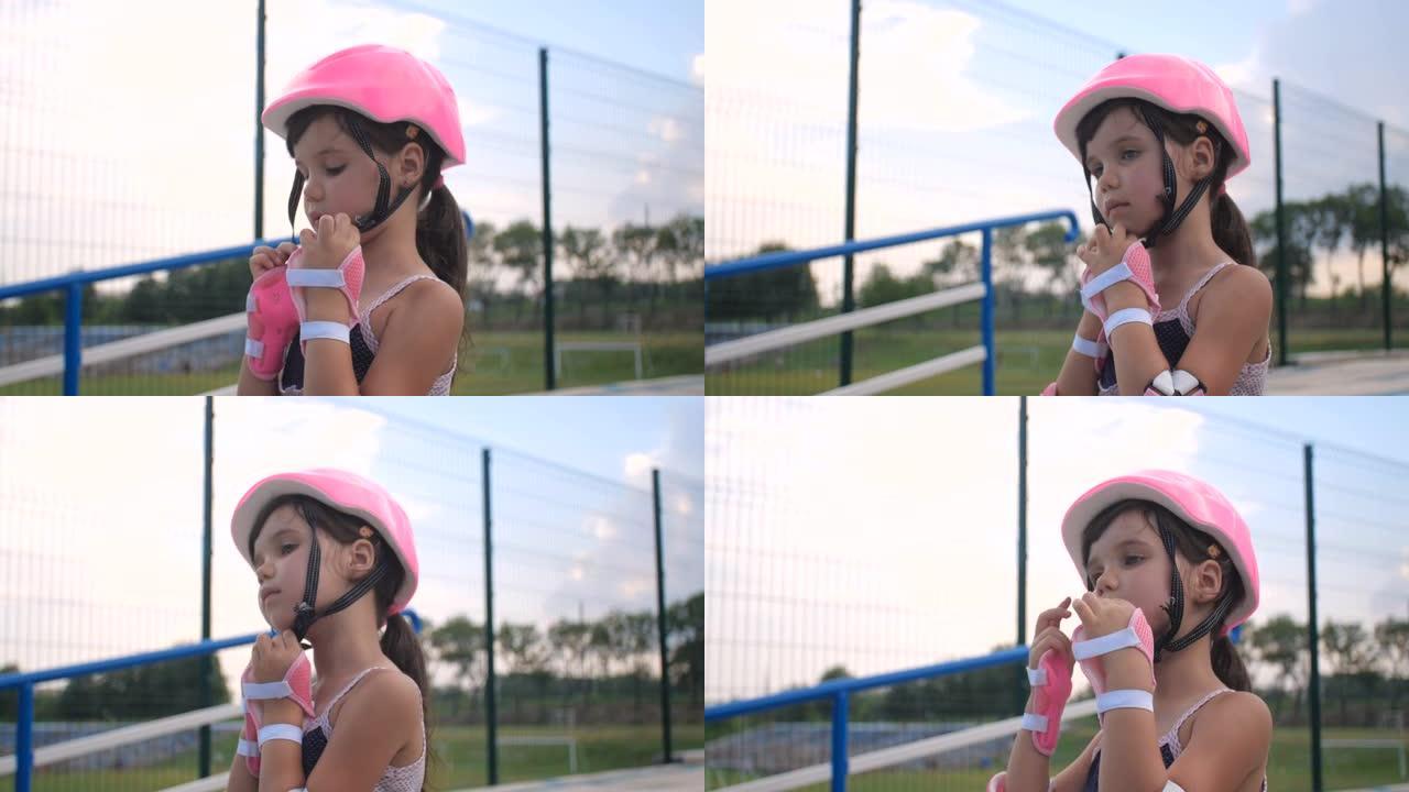 一个小女孩第一次来到轮滑公园学习轮滑。一个学龄前漂亮孩子戴上粉色安全帽的特写肖像，4k慢动作50 F
