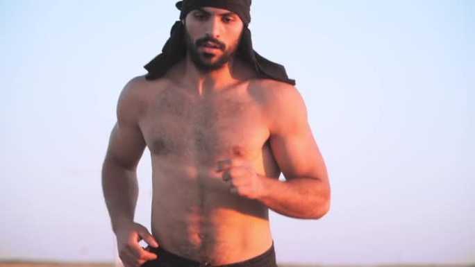 一个肌肉发达，运动健壮的阿拉伯男人，胡须在美丽的日落背景上奔跑。亚洲男跑。户外锻炼中的有氧运动。慢动