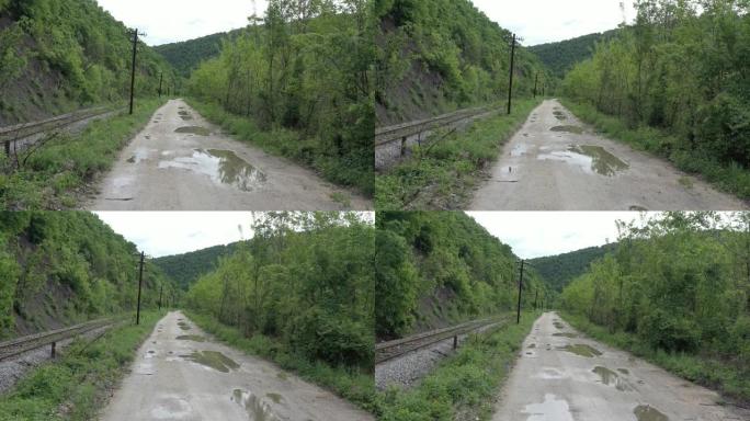 在泥泞的道路上向后飞行，水坑和附近的铁轨4k无人机镜头