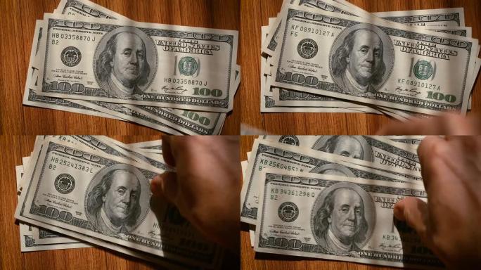 Hand将美国100美元钞票放在桌子上，一张放在另一张上