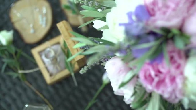 新娘的花束在桌子上，旁边是珠宝盒中的结婚戒指和配饰