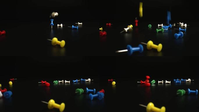 学校和办公室的文具概念。落在黑色表面上的推销。白色、黄色、蓝色、红色和绿色图钉特写。