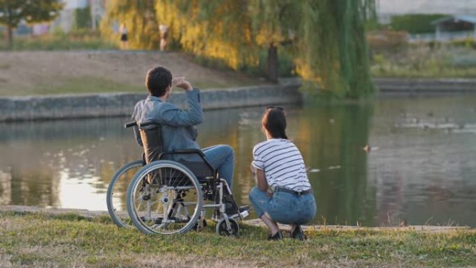 女人和男人坐在轮椅上喂鸭子