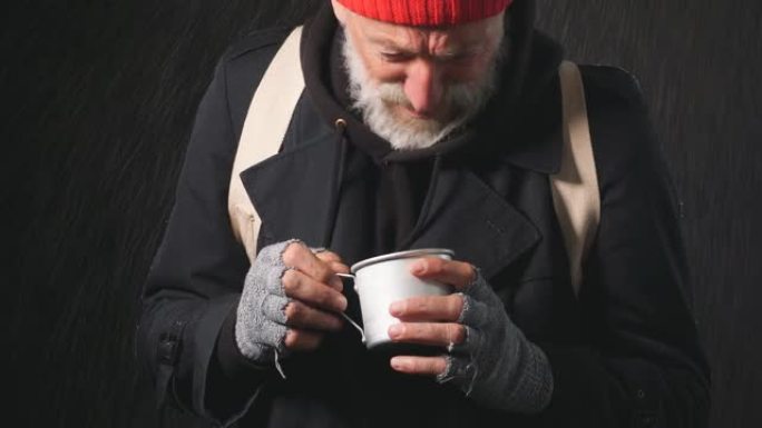 一个成熟的大胡子站在雨中，拿着一个杯子去收钱