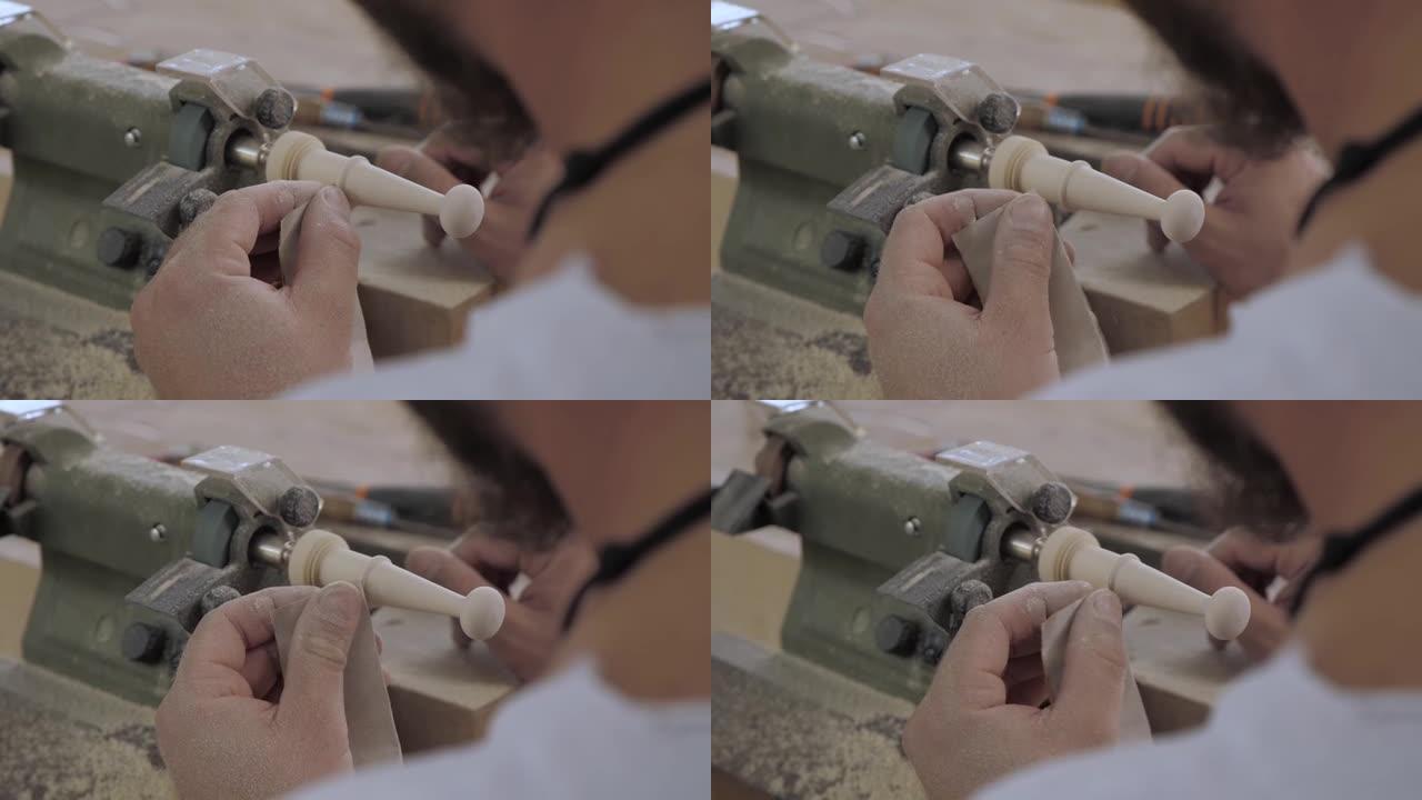 一个专业木匠用砂纸在车床上研磨一块木头的特写镜头。