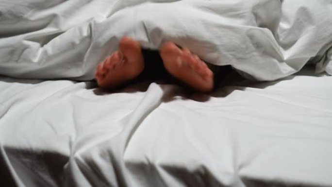 女人的脚在白色的床上盖着毯子