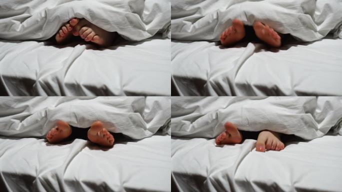 女人的脚在白色的床上盖着毯子
