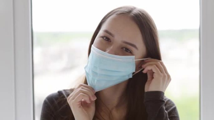 口罩是抗菌医用的。迷人的女孩把她的脸对病毒的补救。一名年轻女子展示了冠状病毒、疾病、细菌的预防