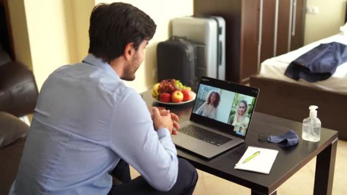 新型冠状病毒肺炎期间，酒店房间里的4k视频商人使用笔记本电脑进行视频会议