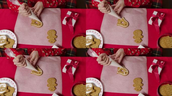 穿着红色新年睡衣的女人的俯视图正在为传统的姜饼饼干锦上添花。用礼品盒装饰的女性手和桌子的特写。为圣诞