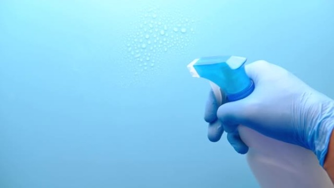 手握蓝色橡胶手套，带复印空间的喷雾瓶