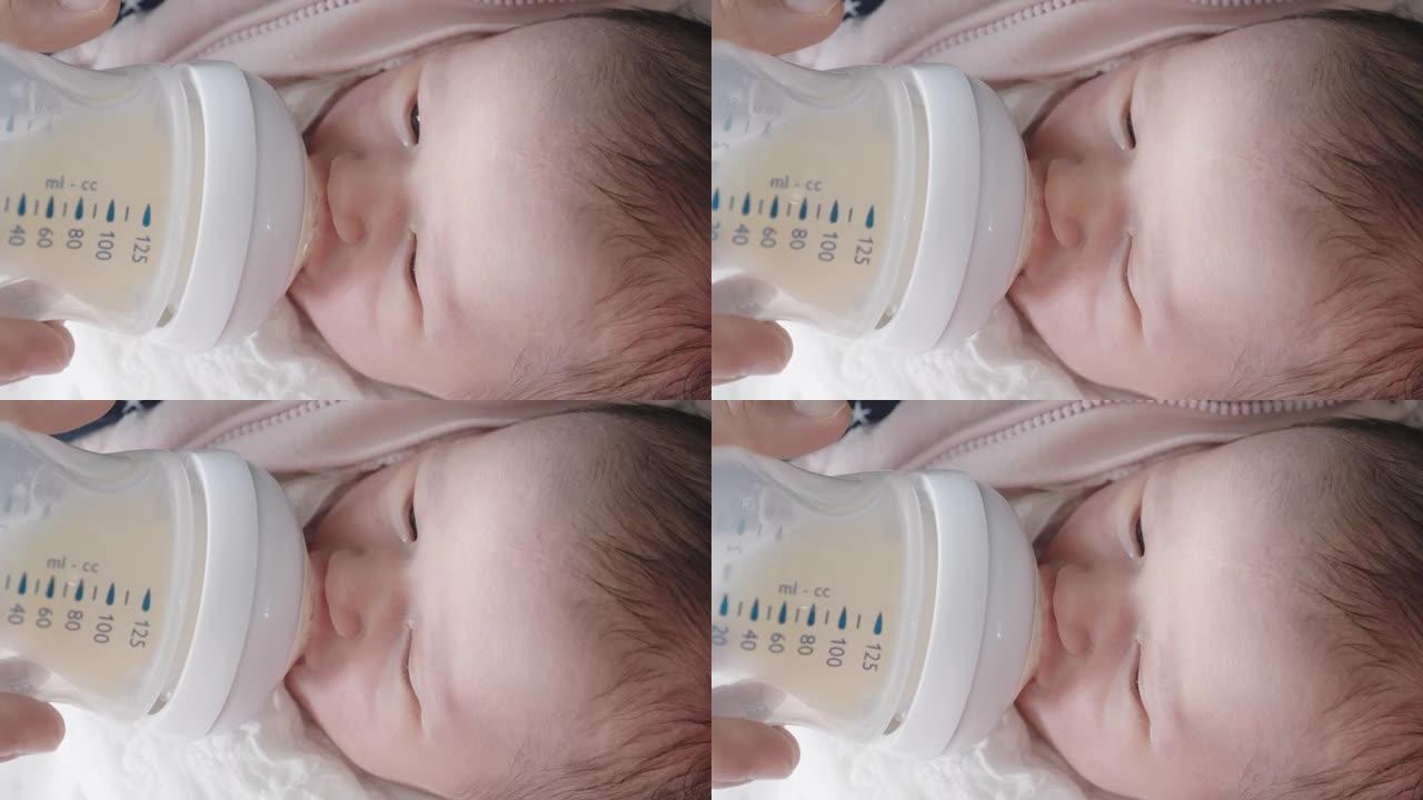 新型冠状病毒肺炎大流行期间的新生婴儿。母亲用奶瓶里的母乳喂养她的女婴。