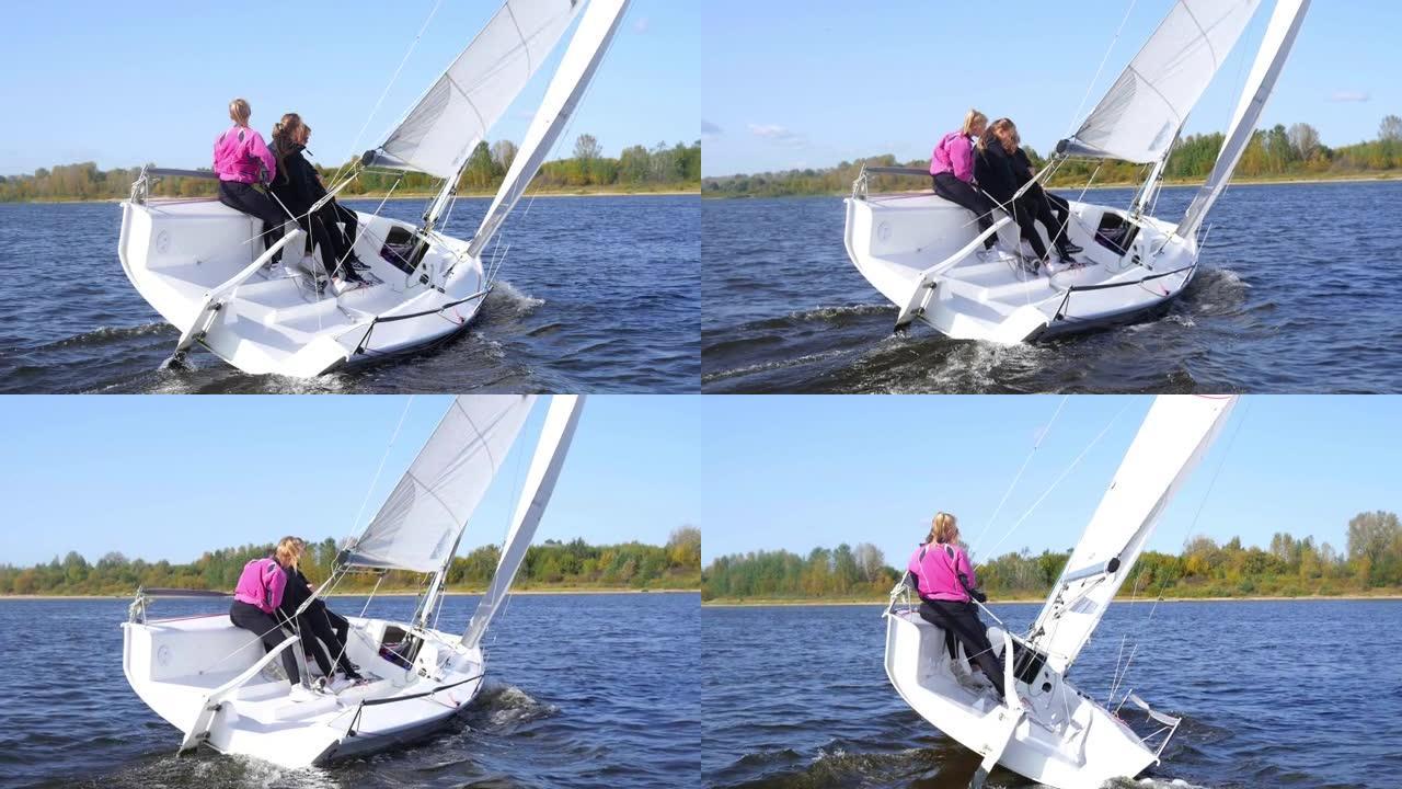 一个男孩和两个女孩通过用脚和手控制帆来演示帆船的转弯