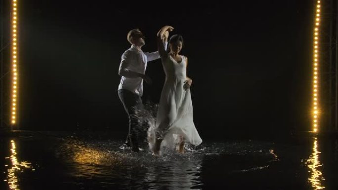 一名身穿白色衬衫的男子和一名身穿白色长裙的女子激情地跳着萨尔萨舞，紧紧地贴着他们的身体。这对夫妇在水