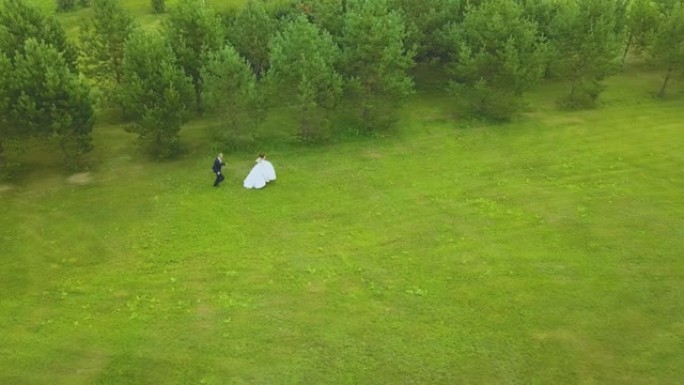 新郎跟随穿着长裙的新娘在野外天线上奔跑