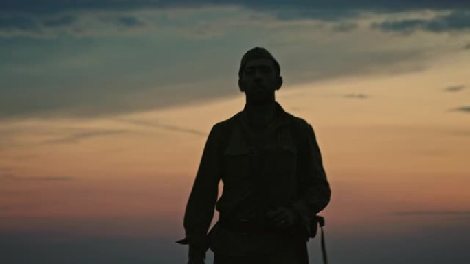 身着制服的士兵在夕阳的映衬下走向摄像机，穿过开阔的乡村