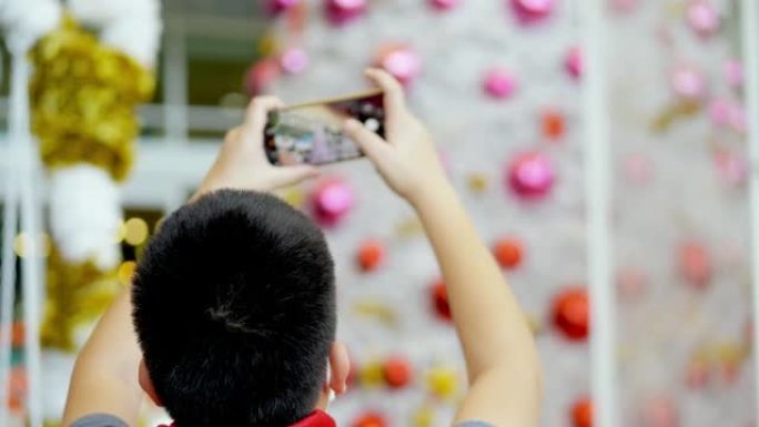 快乐的亚洲男孩戴着口罩和红领巾拍照或自拍自己的圣诞树装饰，节日概念。