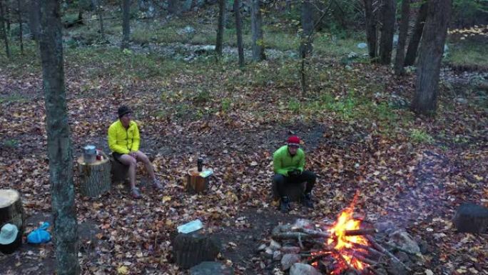两个人坐在篝火旁-森林-秋天