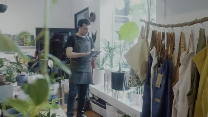 成年工人在他的植物学精品店中检查数字平板电脑上的库存