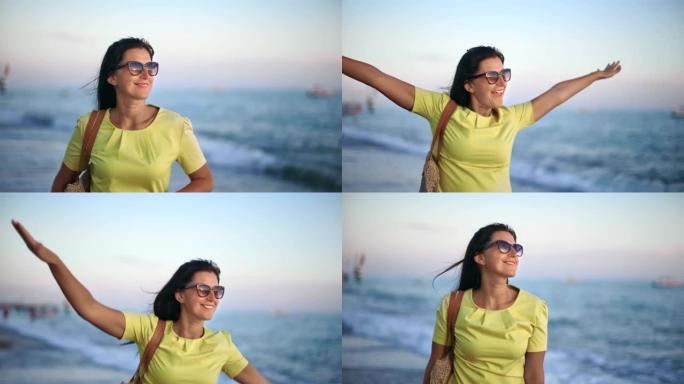 快乐的黑发女士走在傍晚的海滨举起手感觉自由。4k Dragon RED摄像机
