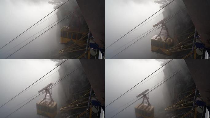 浓雾中的克里米亚-佩特里山脉的缆车。从悬崖到缆车的景色与下降的缆车，在明亮的阳光照亮的云层中的山脉户