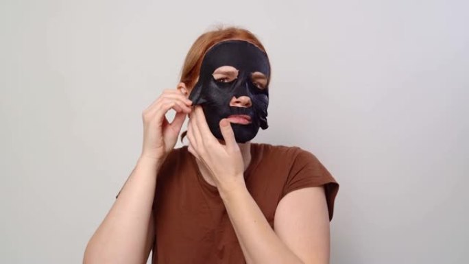 一个女人在脸上戴上黑色化妆面具。