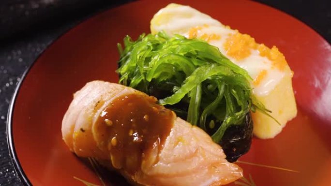 各种寿司，米饭，海藻，烤猪肉，煎蛋，转盘上的鸡蛋。海鲜配料的日本食物。宏观拍摄。