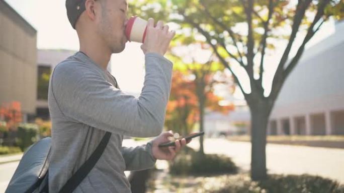 一名日本男子一边用可重复使用的咖啡杯喝咖啡，一边使用智能手机