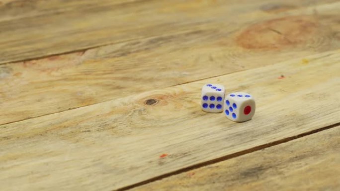 手在木桌上扔了两个骰子。特写
