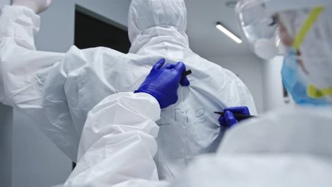 医生在背面写名字，以识别无法识别的同事在防护服中与冠状病毒感染的患者一起工作