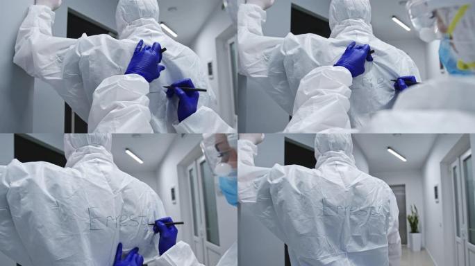医生在背面写名字，以识别无法识别的同事在防护服中与冠状病毒感染的患者一起工作