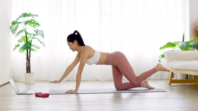 穿着运动服的年轻女子在家在瑜伽垫上进行运动训练