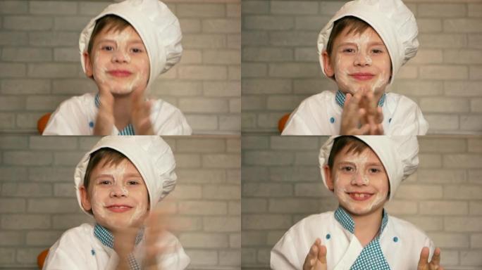 一个戴着帽子的学龄前白人厨师男孩甩掉了手上的面粉。厨房里的孩子开玩笑地帮忙做饭。家庭厨房里的年轻帮手