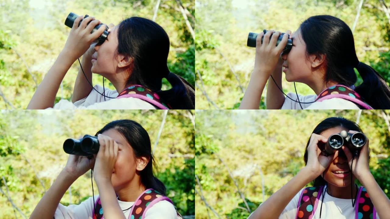 亚洲背包客女孩在与家人度假时使用具有自然背景的双筒望远镜。