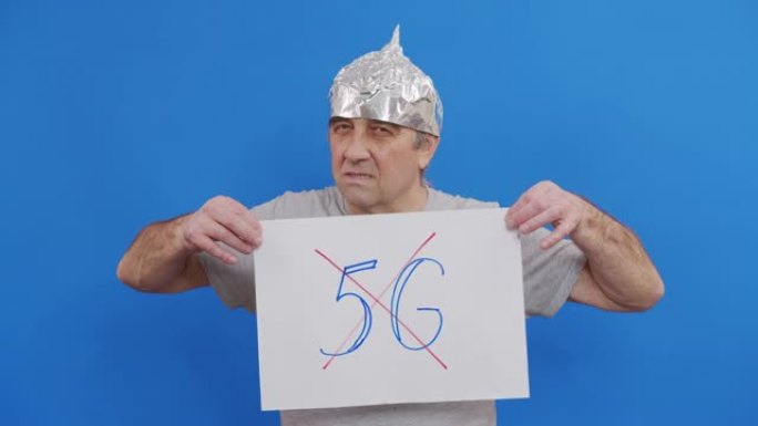 男子举着没有5g标志的标语牌。站在蓝色背景下抗议5g技术和5g兼容天线部署。