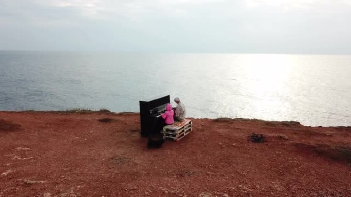 无人机视点-老人和孩子女孩在海滩上弹奏旧钢琴
