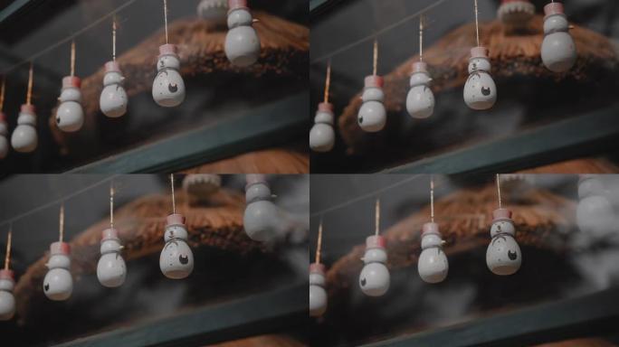圣诞玩具雪人挂在房子玻璃后面的线上