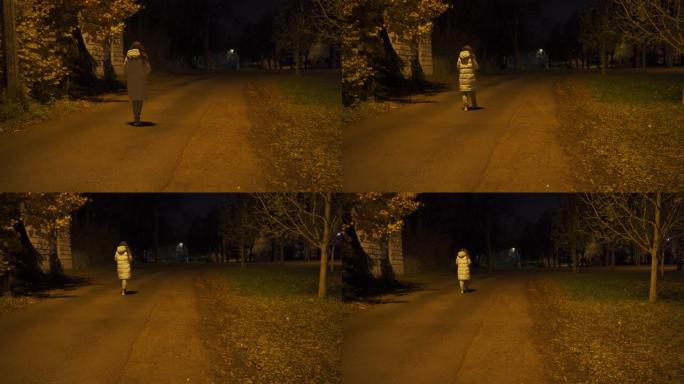 穿着温暖外套的孤独女人走在晚上被灯笼照亮的空人行道上
