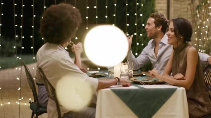 四个人，两对夫妇在浪漫的美食聚会晚餐或午餐期间愉快地谈论饮食。闪亮的灯光。中等镜头。翁布里亚的朋友意