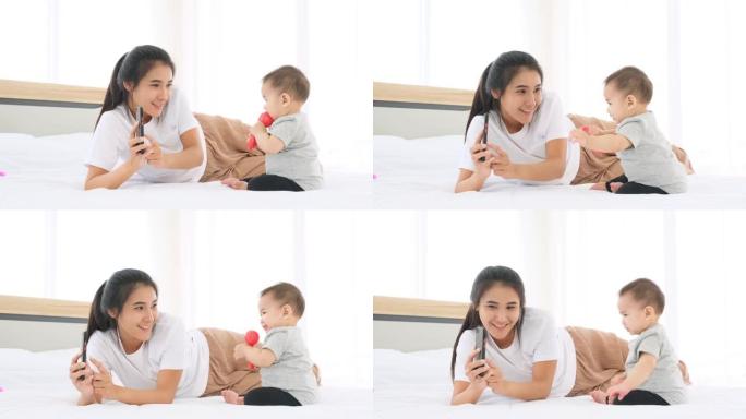 妈妈用智能手机播放卡通电影让小女婴在床上快乐。