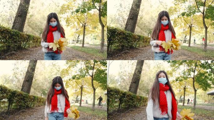 戴着面具和红领巾的时尚女孩边走边捡树叶