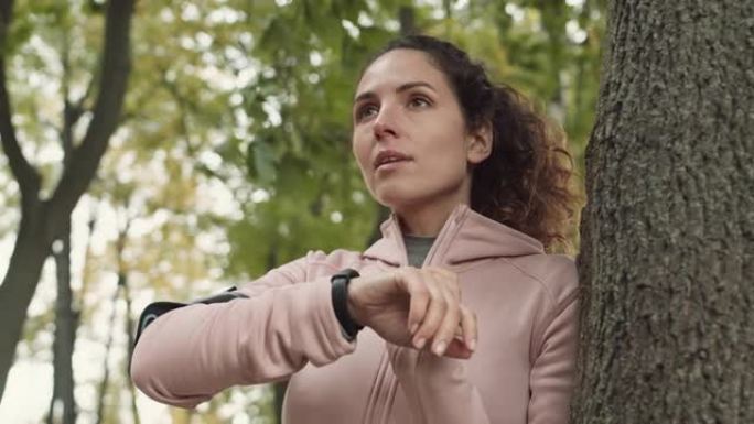 运动女人在森林慢跑前打开智能手表
