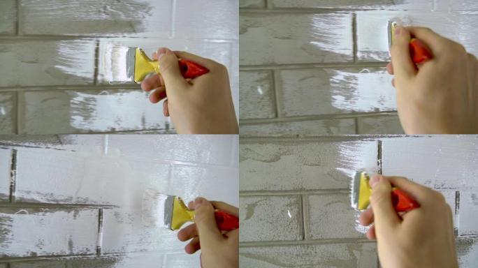一名建筑工人在砖墙上涂油漆。画家用刷子在墙壁上涂底漆，在房屋或房间中进行维修。重建建筑物，专家修复墙