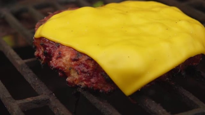 一块切达干酪在肉排上融化，烤架上的汉堡