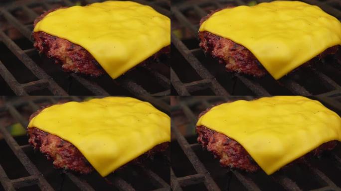 一块切达干酪在肉排上融化，烤架上的汉堡