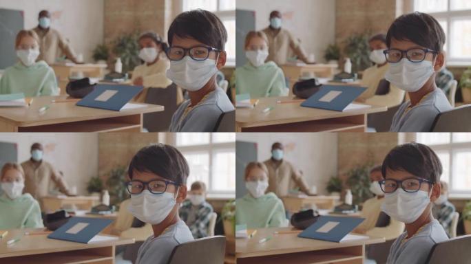 戴着面具的亚洲男生在课堂上为相机摆姿势